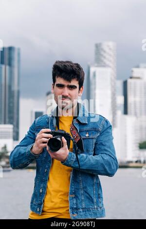 Beau jeune homme en veste denim avec appareil photo Banque D'Images