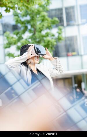 Femme professionnelle avec main levée à l'aide d'un casque de réalité virtuelle Banque D'Images