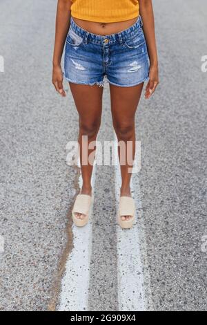 Jeune femme portant un short en denim debout sur la route Banque D'Images