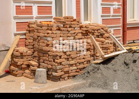 Piles de vieilles briques rouges de construction dispersées dans la rue. Bâtiment Banque D'Images