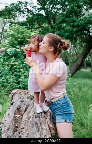 Mère et fille soufflant des bulles dans le parc Banque D'Images