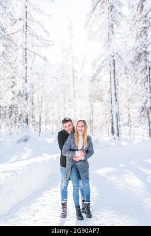 Couple heureux embrassant sur la neige pendant les vacances Banque D'Images