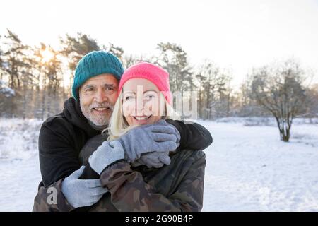 Homme âgé souriant debout avec le bras autour de la femme pendant l'hiver Banque D'Images