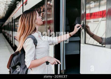 Jeune femme passager appuyant sur le bouton du train à la gare Banque D'Images