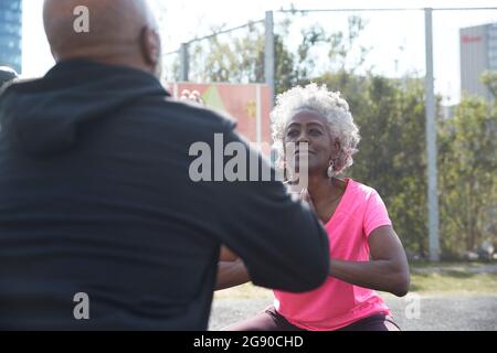 Femme regardant l'homme pendant qu'elle se squat dans le parc Banque D'Images