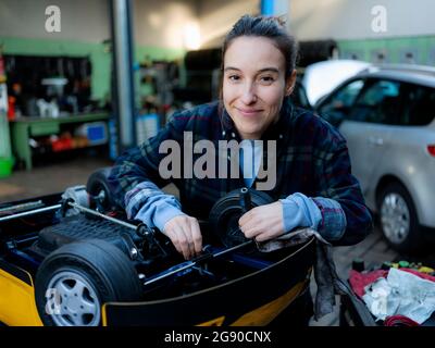 Femme mécanicien travaillant sur une voiture-jouet à l'atelier Banque D'Images