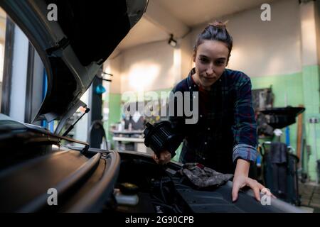 Femme mechanic repairing car lors de l'atelier Banque D'Images