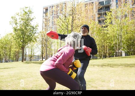 Couple pratiquant la boxe au parc le jour ensoleillé Banque D'Images