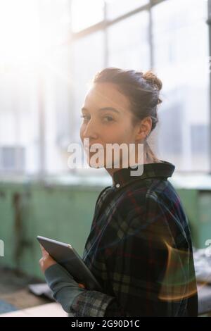 Femme mécanicien avec tablette numérique debout à l'atelier Banque D'Images