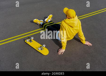 Rubans adhésifs jaunes sur les jambes de garçon par planche à roulettes sur la route Banque D'Images