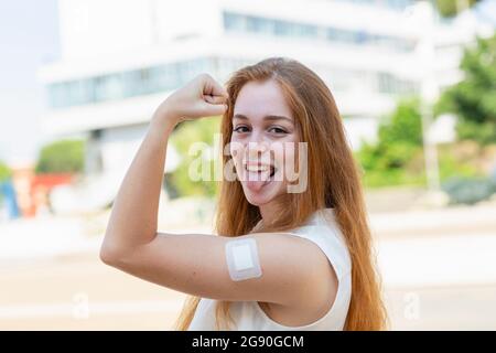 Femme d'affaires avec bandage sur le bras qui dépasse la langue pendant une pandémie Banque D'Images