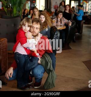 Belle Natalia Vodianova look-semblables petite fille en chandail rouge et jeans + jouet dans les mains photographiés avec son père à la présentation de mode à Kiev Banque D'Images