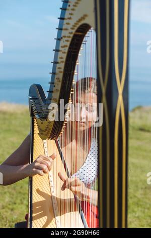 Jeune femme jouant de la harpe le jour ensoleillé Banque D'Images