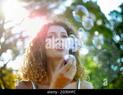 Jeune femme faisant des bulles au parc Banque D'Images