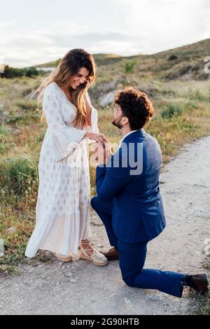 Bonne femme regardant le petit ami proposer en s'agenouillant Banque D'Images