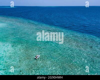 Maldives, vue aérienne d'un seul bateau à moteur flottant sur les eaux turquoises de l'océan Indien en été Banque D'Images
