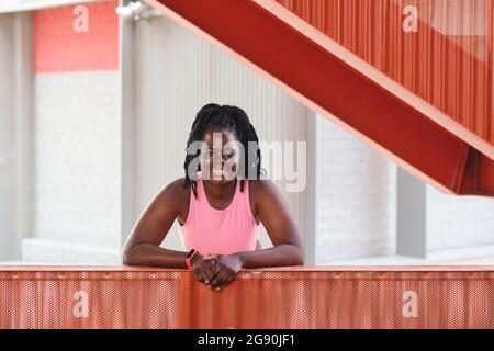 Jeune femme souriante et de taille plus penchée sur une main courante brune Banque D'Images