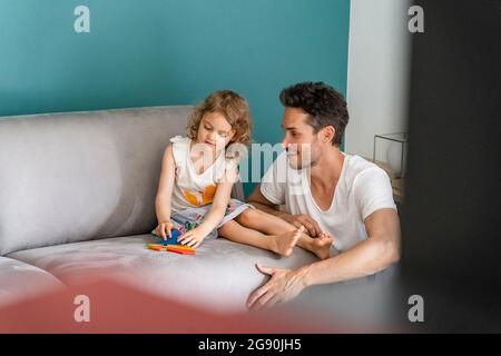 Fille jouant avec le puzzle tout en étant assis par le père dans la salle de séjour Banque D'Images