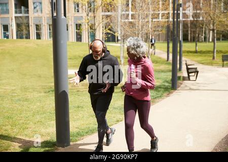 Homme en faisant des gestes tout en faisant du jogging avec une femme âgée dans le parc Banque D'Images