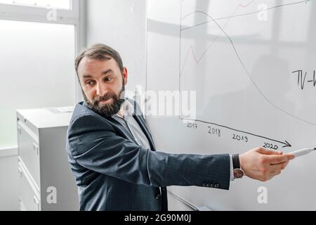 Homme d'affaires expliquant le graphique sur le tableau blanc au bureau Banque D'Images