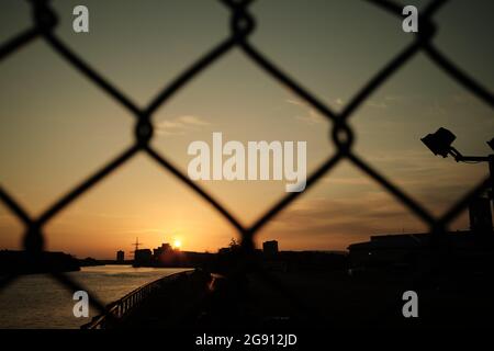 Coucher de soleil couvert par la clôture. Vue sur la rivière Clyde, Glasgow. Été 2021. Banque D'Images