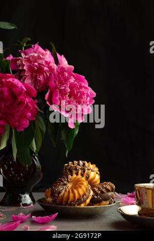 Biscuits, tasse de thé et vase avec fleurs sur fond noir Banque D'Images