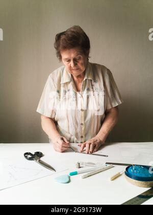 La femme âgée construit un modèle de masque médical sur le papier Banque D'Images