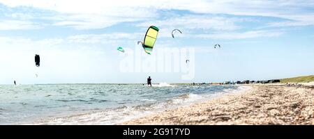 Vue panoramique de beaucoup de gens aiment faire du kite surf planche dans un costume de protection uv de soleil sur une journée ensoleillée à la mer ou sur la côte de l'océan kitesurf camp spot Banque D'Images