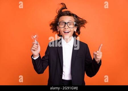 Photo de l'excitée excitée heureux garçon point de doigt tenir l'idée de plan isolé sur fond orange de couleur Banque D'Images