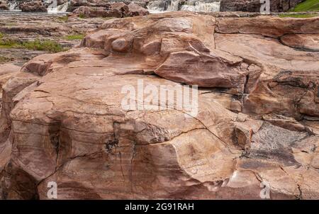 Sioux Falls, Dakota du Sud, États-Unis - 2 juin 2008 : gros plan d'une grande roche brune en cascade. Un peu d'eau mousseuse dans le dos. Usure polie sur la surface clea Banque D'Images