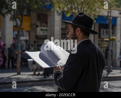 Jérusalem, Israël - 21 juillet 2021 : un juif orthodoxe lisant un livre de Mishna sur une rue de Jérusalem, Israël, un jour ensoleillé. Banque D'Images