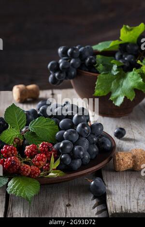 Raisins frais dans une assiette en argile sur une vieille table rustique. Banque D'Images