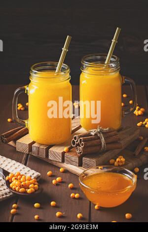 Deux tasses de thé d'argousier sur une table en bois avec de la cannelle, de l'argousier et du miel. Concept de boisson médicinale pour la santé et chaud Banque D'Images