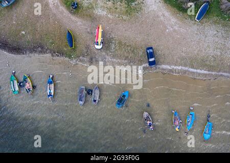 Vue aérienne des bateaux de pêche traditionnels en bois et de certaines voitures des habitants de la région sur le lac Prespa en Albanie Banque D'Images