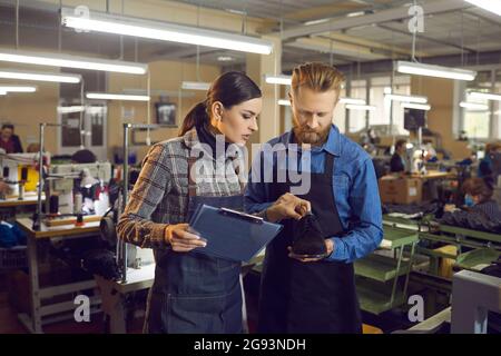 Femme maître avec presse-papiers pour vérifier la présence d'un défaut dans les mains du cordonnier Banque D'Images