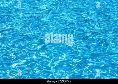 Eau ondulée dans la piscine avec reflet de soleil. Fond d'eau. Banque D'Images