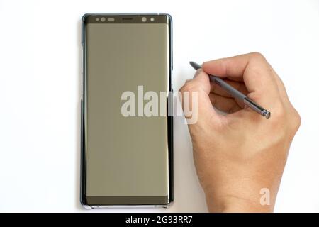 BANGKOK, THAÏLANDE - 23 décembre 2017 : homme d'affaires tient le stylet pour écrire à Samsung Galaxy Note 8 sur fond blanc. C'est le fleuron smartph Banque D'Images