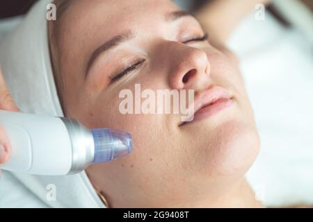 gros plan portrait d'une femme heureuse à tête rouge avec les yeux fermés obtenant rf-levage dans un salon de beauté Banque D'Images