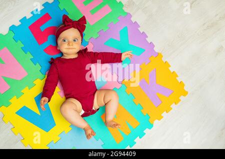 Petite fille de bébé a posé sur la moquette ABC de couleur Banque D'Images