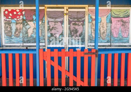 Vue sur le paysage d'une hutte de plage peinte dans des maillots de bain en se tenant dans la mer, Sutton-on-Sea, Lincolnshire, Royaume-Uni, juin Banque D'Images