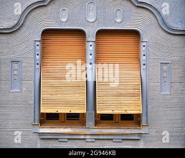 Détail de deux fenêtres avec vieux volets en bois ou en métal sur un mur gris Banque D'Images