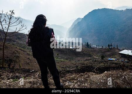 jeune fille regardant la vallée de montagne brumeuse avec des rayons du soleil le matin à partir d'un angle plat Banque D'Images