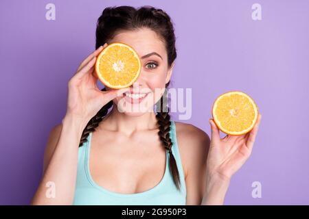 Portrait de mignon doux brun cheveux femme montre les oranges porter bleu haut isolé sur pastel couleur violet fond Banque D'Images