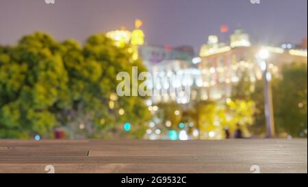 Table en bois sur des bâtiments flous dans le fond de la ville de nuit. Pour l'affichage du produit de montage ou la présentation visuelle clé. Banque D'Images