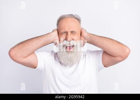 Portrait d'un homme d'âge moyen, fou et attrayant, qui ferme les oreilles en criant des hurleurs isolés sur un fond blanc pastel Banque D'Images