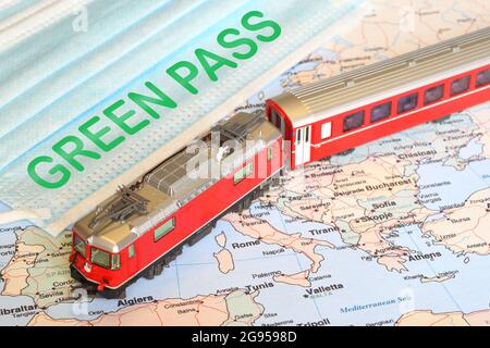 surgìcal masques avec le texte VERT PASSENT sur une carte géographique et un modèle de train rouge. Concept de voyage sécurisé pendant le coronavirus avec Green Pass Banque D'Images