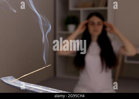 Un bâton indien aromatique est en train de brûler, la femme en arrière-plan est méditant. L'aromathérapie, l'auto-immersion, le pouvoir de la pensée Banque D'Images