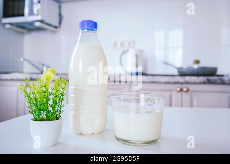 une bouteille de lait et une tasse en verre sur la table de cuisine en arrière-plan du mur de cuisine léger et confortable Banque D'Images