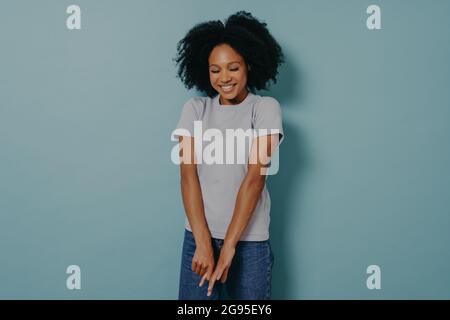 Jeune femme africaine regardant vers le bas avec timide expression de visage, isolé sur fond bleu Banque D'Images