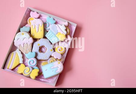 Biscuits de fête d'épices colorés de différentes formes couverts de glaçure sur fond rose copie espace. Banque D'Images
